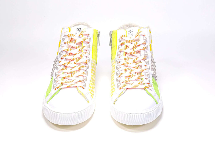 Front view of mid top sneaker. Patchwork upper of mixed materials and silver studs.