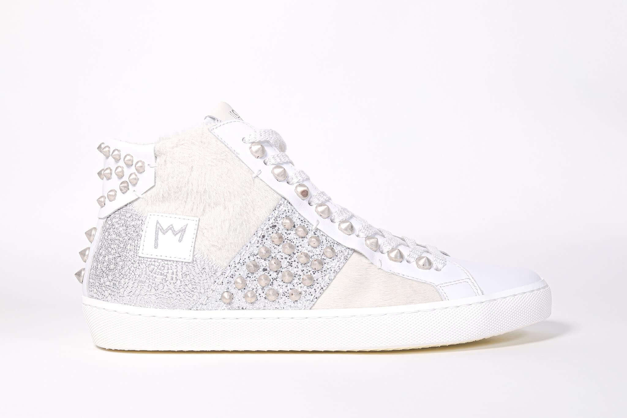 Side profile of mid top sneaker. Patchwork upper of mixed materials and silver studs.
