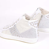 Three quarter back view of mid top sneaker. Patchwork upper of mixed materials and silver studs.