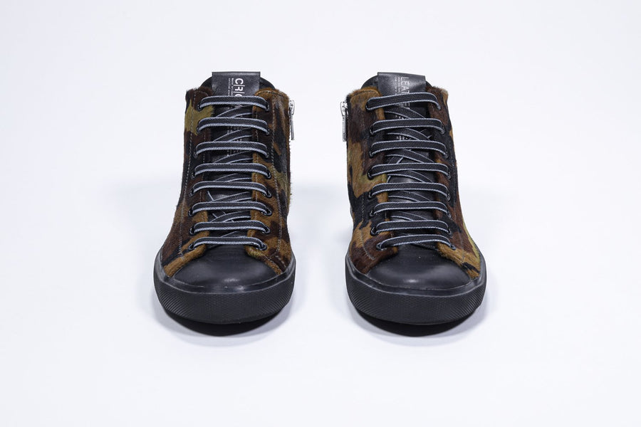Vorderansicht eines Mid-Top-Sneakers mit Camouflage-Print, Obermaterial aus Kalbsleder, innerem Reißverschluss und schwarzer Sohle.