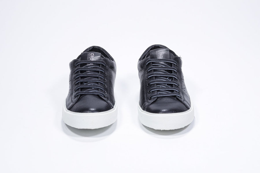 Vorderansicht eines schwarzen Low-Top-Sneakers mit perforiertem Kronenlogo auf dem Obermaterial. Obermaterial aus Vollleder und weiße Gummisohle.