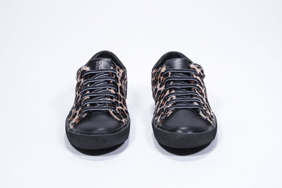 Vorderansicht eines Low-Top-Sneakers mit Leopardenmuster. Obermaterial aus Haarkalbsleder und schwarze Gummisohle.