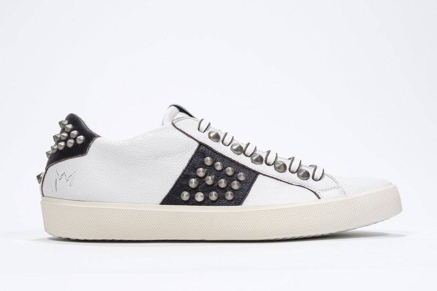 Weiß-schwarzer Low-Top-Sneaker im Seitenprofil. Obermaterial aus Vollleder mit Nieten und Vintage-Gummisohle.