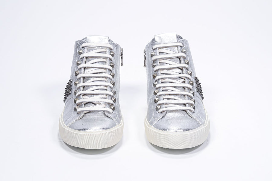 Vue de face d'une chaussure de sport intermédiaire en argent métallisé. Tige en cuir avec clous, fermeture éclair intérieure et semelle en caoutchouc vintage.