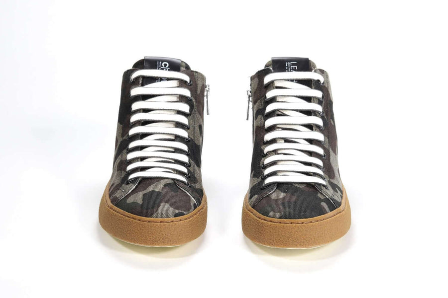 Vista frontale della sneaker mid top con stampa mimetica, tomaia in tela, zip interna e suola in gomma riciclata color miele.