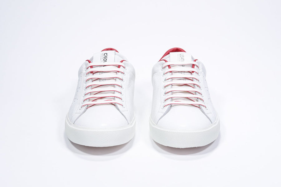 Vista frontale della sneaker low top bianca con dettagli rossi e logo della corona traforato sulla tomaia. Tomaia in pelle e suola in gomma bianca.