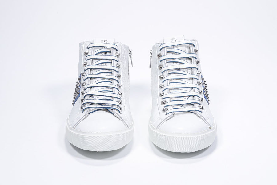 Vista frontale della sneaker mid top bianca e blu royal. Tomaia in pelle con borchie, zip interna e suola in gomma bianca.