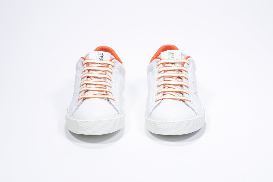 Vista frontale della sneaker low top bianca con dettagli arancioni e logo della corona traforato sulla tomaia. Tomaia in pelle e suola in gomma bianca.