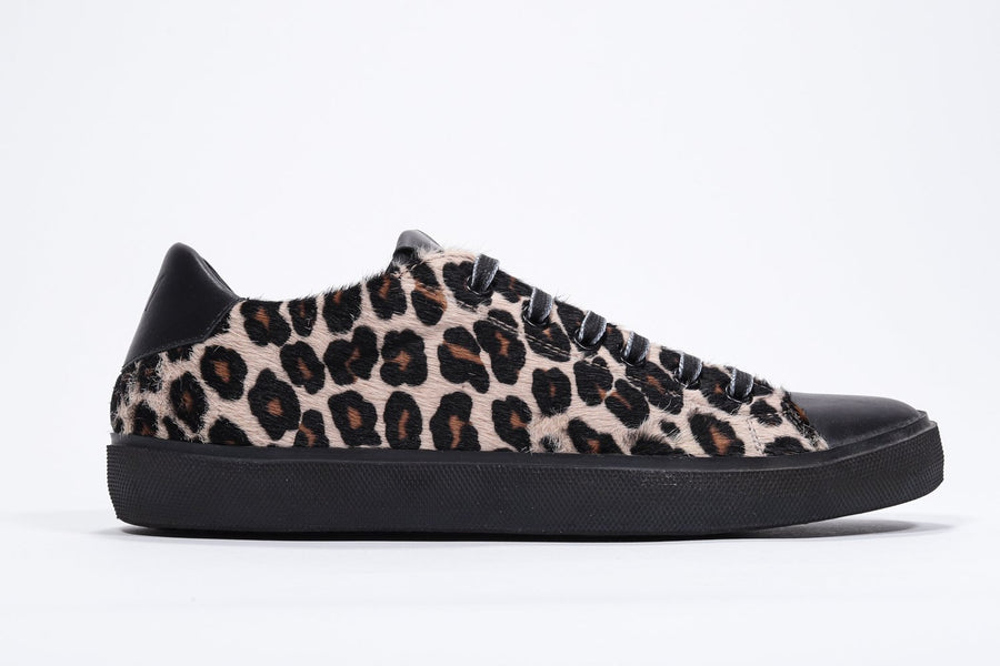 Profilo laterale di una sneaker bassa con stampa leopardata. Tomaia in pelle di vitello e suola in gomma nera.