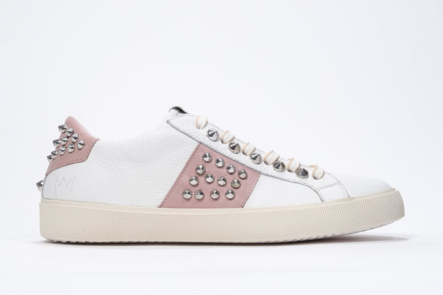 Profilo laterale di una sneaker low top bianca e rosa pallido. Tomaia in pelle con borchie e suola in gomma vintage.