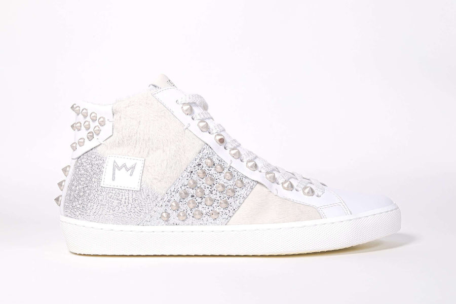 Profilo laterale di una sneaker mid top. Tomaia patchwork di materiali misti e borchie argentate.